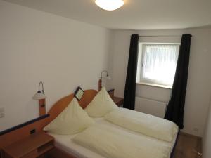 a bed with white pillows in a room with a window at Büchelsteiner Hof in Grattersdorf