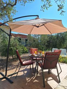 een tafel en stoelen onder een parasol op een patio bij Marija Holiday Home in Sućuraj