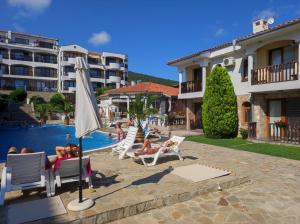 a group of people laying in lawn chairs by a pool at Sun Coast Apartment in Sveti Vlas