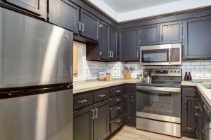 een keuken met zwarte kasten en een roestvrijstalen koelkast bij Entire condo in downtown winston in Winston-Salem