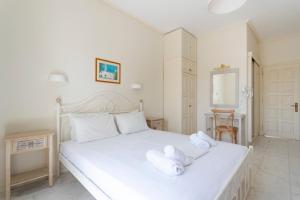 a bedroom with a white bed with towels on it at Villa Kalomira in Spetses