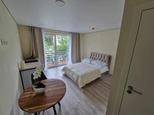 Schlafzimmer mit einem Bett, einem Tisch und einem Fenster in der Unterkunft 2rest in Palanga