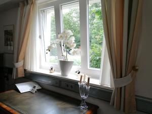 ein Fenster mit einer Vase Blumen auf einem Tisch in der Unterkunft Claas Villa am Meer in Bad Zwischenahn