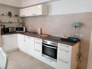 a kitchen with white cabinets and a stove top oven at Claas Villa am Meer in Bad Zwischenahn