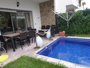 a patio with a swimming pool and a table and chairs at Villa Sidi Rahal Casablanca in Sidi Rahal