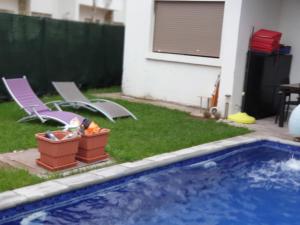 une arrière-cour avec une piscine, 2 chaises longues et une maison dans l'établissement Villa Sidi Rahal Casablanca, à Sidi Rahal