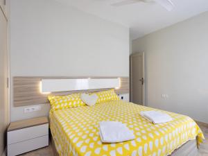 a bedroom with a yellow bed with two towels on it at Live Basilica Candelaria Beach & Balcony in Candelaria