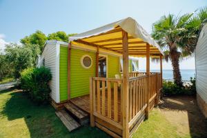 a green and white house with a deck at Alannia Costa Dorada in Platja de l’Almadrava