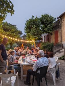 eine Gruppe von Menschen, die an einem Tisch im Garten sitzen in der Unterkunft Le Grand Saint Mitre in Saint-Maximin-la-Sainte-Baume