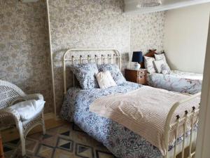 a bedroom with two beds and a chair at La Barboulotte in Saint-Léger-Vauban