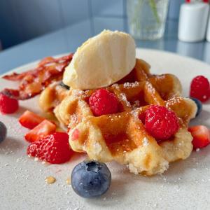 a waffle with a banana and berries on a plate at Tusker Lodge in Torquay