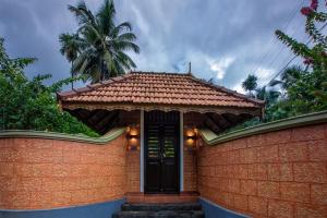 a brick house with a black door and a palm tree at Sukrutham Farmstay in Trichūr +39 photos