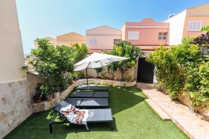 una imagen de un patio trasero con sombrilla y bancos en Comfortable 4-Bedroom Villa with Private Gardens, en Adeje