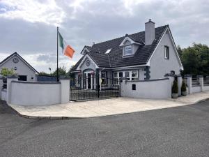 a house with a fence and a flag in front of it at Kev's Place in Keshcarrigan