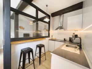 una cocina con armarios blancos y taburetes negros en Estudio loft moderno muy céntrico, en Santander