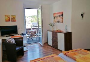 a living room with a television and a desk with a chair at Pension Stern in Rauenberg