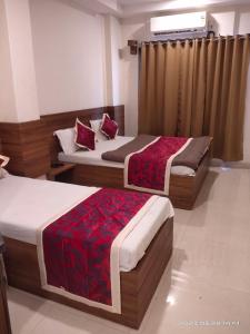 two beds in a hotel room with red pillows at HOTEL SAI PRABHU INN in Shirdi