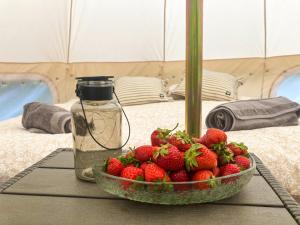 eine Schale Erdbeeren auf einem Tisch neben einem Glas in der Unterkunft Mazury Glamping Kruklanki Polana Życzeń in Kruklanki