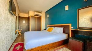 sypialnia z białym łóżkiem i niebieską ścianą w obiekcie Hôtel Belle Vue et Spa w mieście Meknès