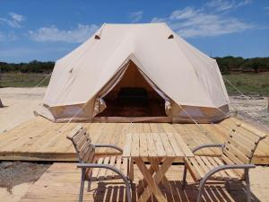 ein großes Zelt mit 2 Stühlen und einem Holztisch in der Unterkunft COMPORTA Side Tends in Setúbal