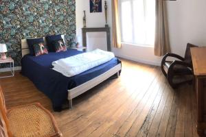 1 dormitorio con cama con sábanas azules y ventana en Maison-Gite Chez Roland, en Distré