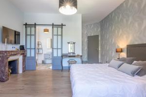 a bedroom with a large white bed and a fireplace at le clos grillet in La Chambre