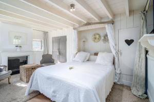 a bedroom with a white bed and a fireplace at Guesthouse B&B De Loverlij in Jabbeke