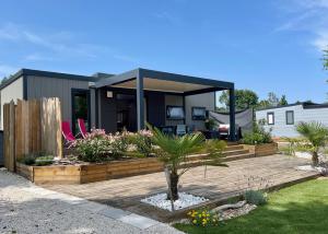 een huis met een houten terras in een tuin bij Charming ecolodge with heated pool in Charente-Maritime in Les Mathes