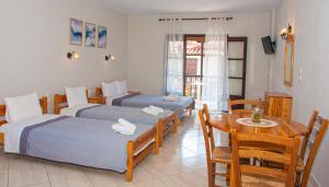 a hotel room with two beds and a table and a dining room at Aris Junior Studios Neo Klima Skopelos in Neo Klima