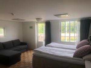 a bedroom with two beds and a couch and a window at Skulesjön Hotell in Bjästa