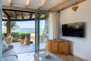 a living room with a couch and a tv at Villa Baja Sardinia con piscina e vista in Baja Sardinia