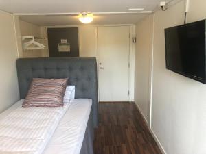 um pequeno quarto com uma cama e uma televisão de ecrã plano em Skulesjön Hotell em Bjästa