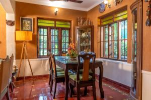 a dining room with a table and chairs and windows at Sukrutham Farmstay in Trichūr