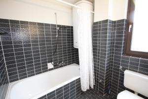 a bathroom with black tiled walls and a bath tub at Ferienwohnung Königsleiten 63 - Top 18 in Königsleiten