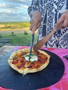 a person is cutting a pizza with a knife at La Vignerie in Boisse