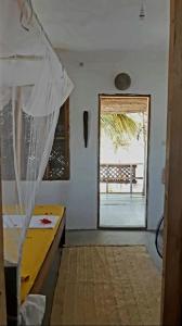 a room with a bed and a window and a table at Mango Beach House in Jambiani