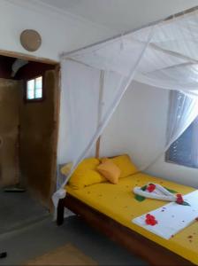 1 dormitorio con 1 cama amarilla con dosel en Mango Beach House en Jambiani