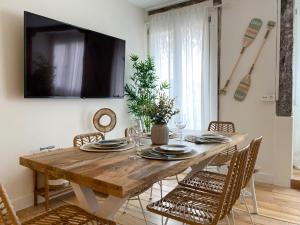 a dining room table with chairs and a television on a wall at Salazar by Staynnapartments in Bilbao