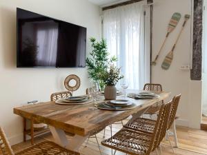stół jadalny z krzesłami i telewizor na ścianie w obiekcie Salazar by Staynnapartments w mieście Bilbao