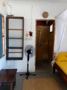um quarto com uma ventoinha e um quarto com uma cama em Mango Beach House em Jambiani