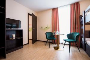 リングスハイムにあるHotel La Toscana Nähe Europaparkのベッド、テーブル、椅子が備わるホテルルームです。