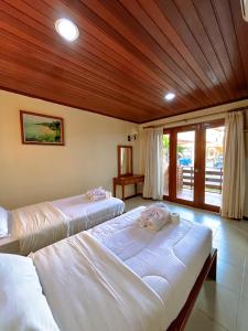 two beds in a room with wooden ceilings at Arbiru Beach Resort in Dili