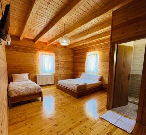 a bedroom with two beds in a wooden cabin at Bujtina Dini in Rubik +10 photos