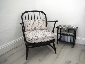 a chair with a pillow next to a side table at Pheasants Wander in Newquay