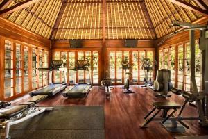 The Oberoi Beach Resort, Bali في سمينياك: صالة ألعاب رياضية مع العديد من آلات المشي في غرفة مع نوافذ