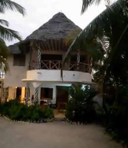 a house with a palm tree in front of it at Mango Beach House in Jambiani