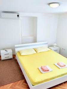 a bedroom with a yellow bed with two towels on it at Apartments Grkinić in Karlobag