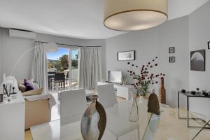 sala de estar con muebles blancos y mesa de cristal en Apartamento en complejo con piscina, pádel y restaurante con vistas al golf en Mijas - Matchroom 83, en Fuengirola