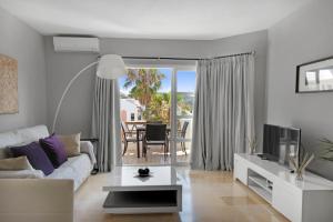 a living room with a couch and a table at Apartamento en complejo con piscina, pádel y restaurante con vistas al golf en Mijas - Matchroom 83 in Fuengirola