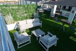 un patio con sofá, 2 sillas y una mesa en Hotel Málaga Nostrum Airport en Málaga